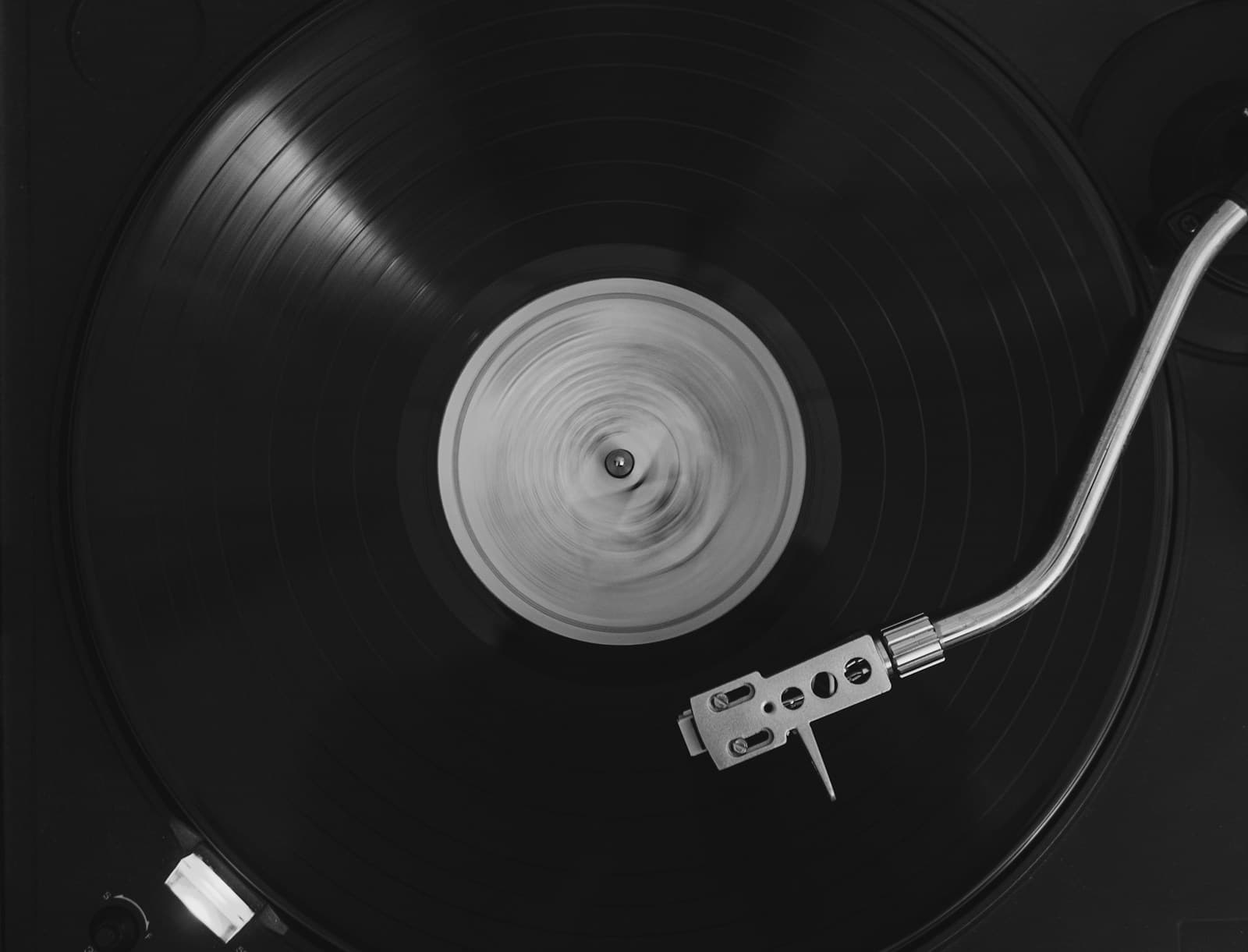Bras de lecture posé sur un disque vinyle, lumière rasante